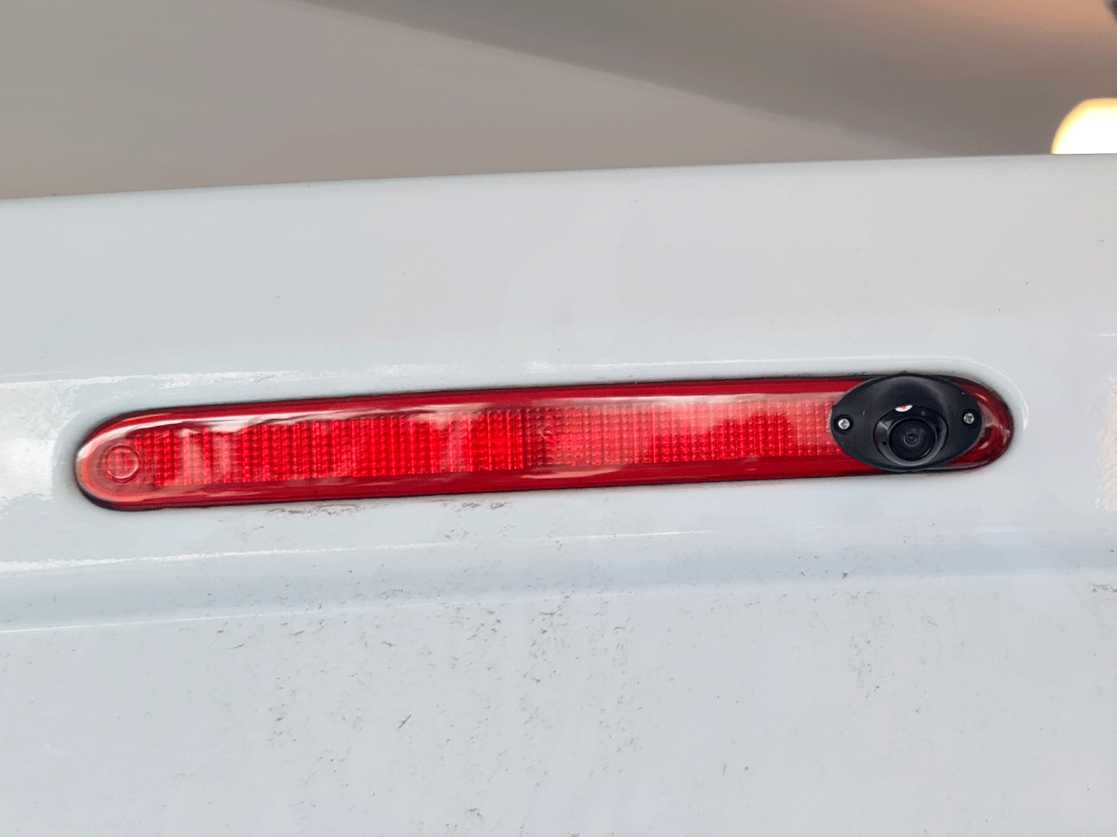 3040007_3_3040007_3.png Rear taillight on a white car with a small backup camera mounted beside it (for reversing).